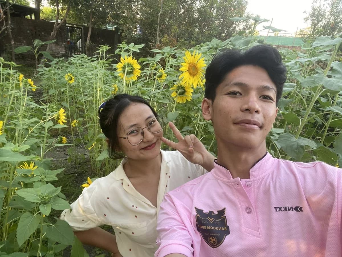Htet and Gloria smiling among sunflowers