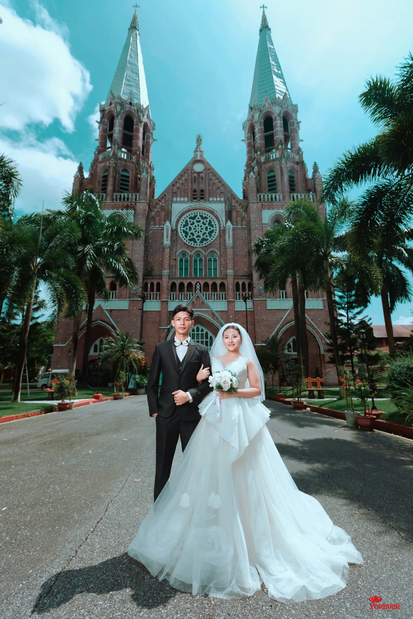 Htet and Gloria before a red-brick cathedral